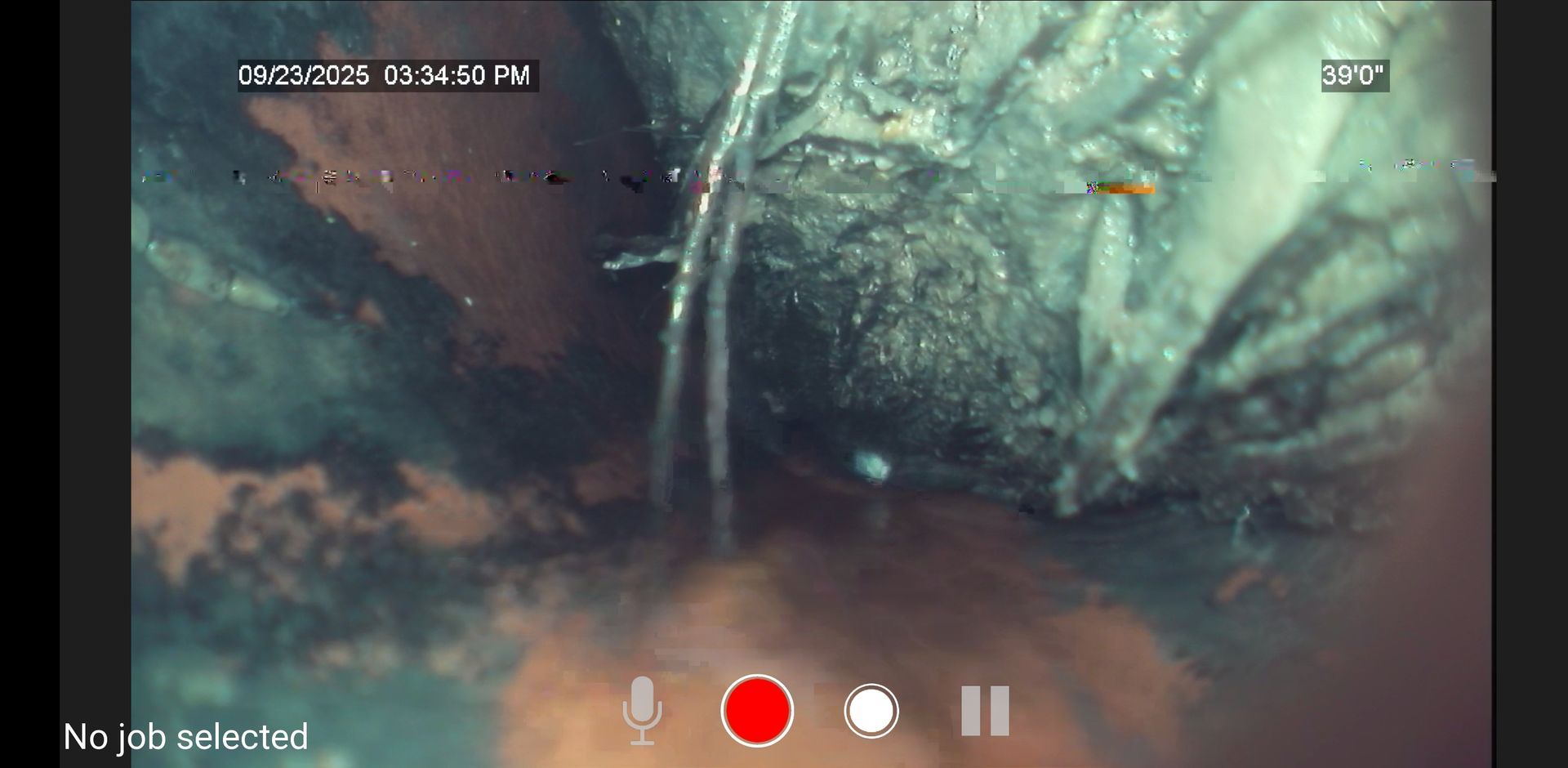 Close-up of a dark, rocky cave wall with water or mud in the foreground and camera recording icons overlaid.