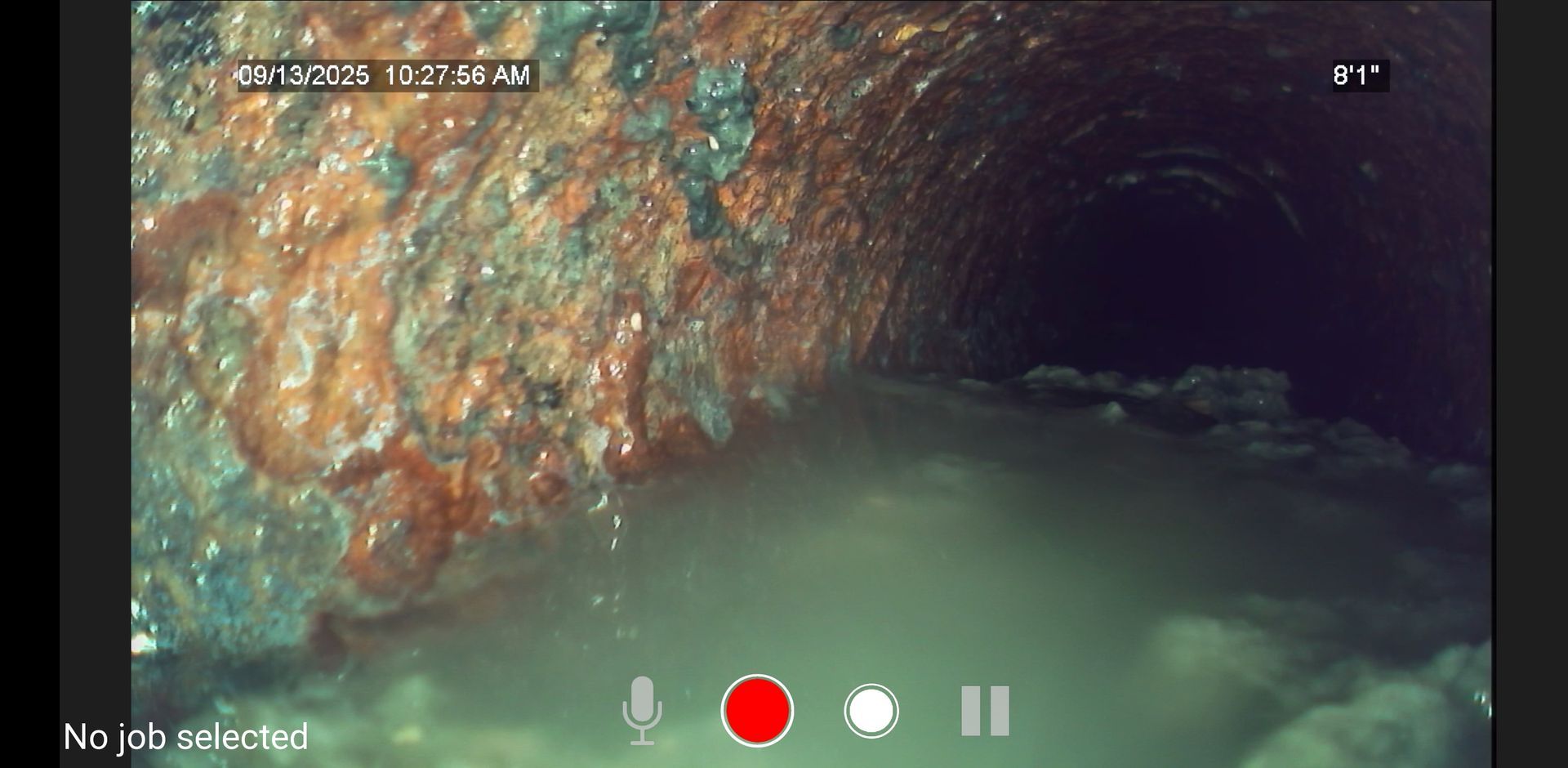 Underwater view inside a narrow rocky cave with murky water and camera controls visible
