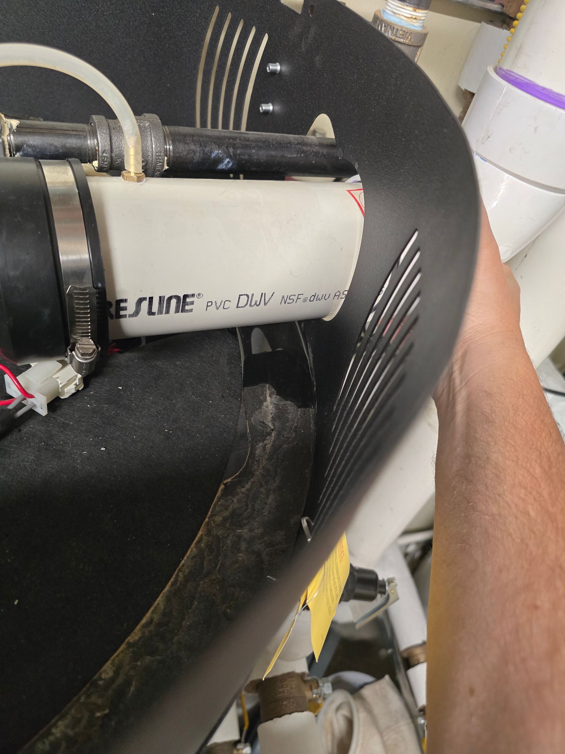 Close-up of a gray and black device strapped to a black chair, with a person’s arm beside it.