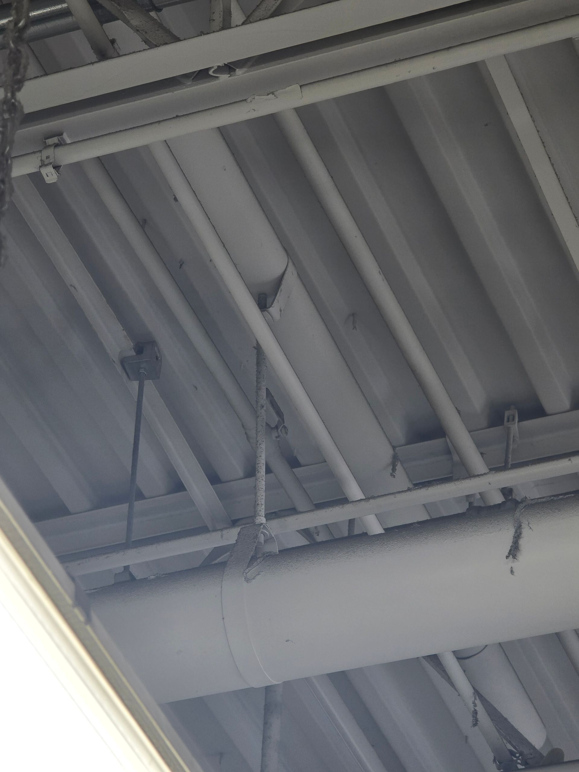 Industrial ceiling with metal beams, pipes, and fluorescent lights