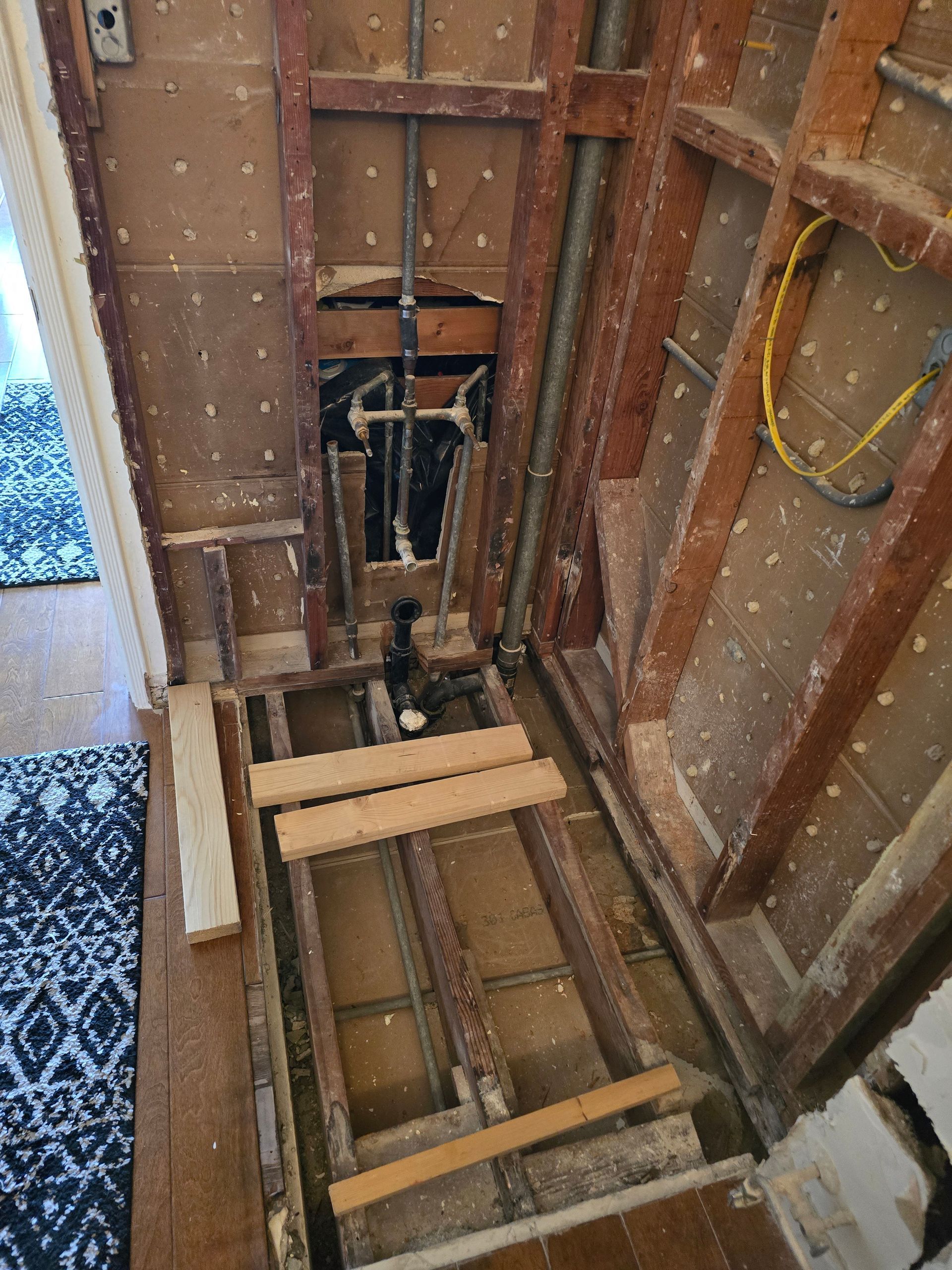 Open floor joists around a stairwell opening, with exposed wiring and wood framing inside a house.