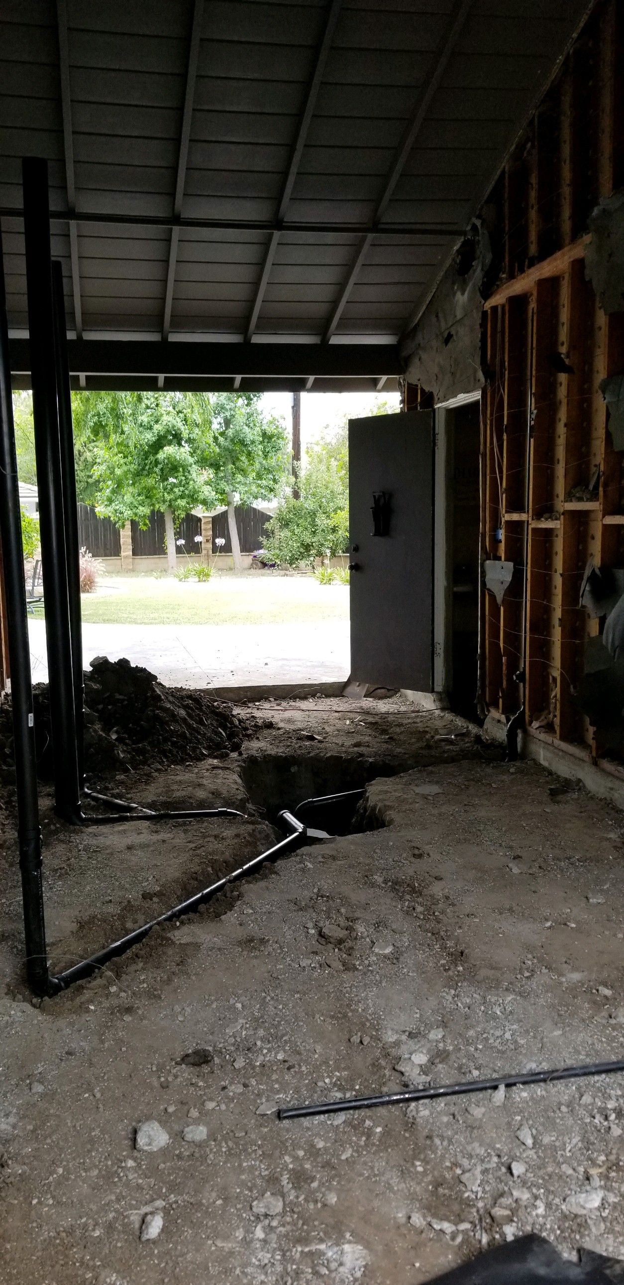 Partially built interior with rubble on the floor and a bright outdoor opening beyond a doorway