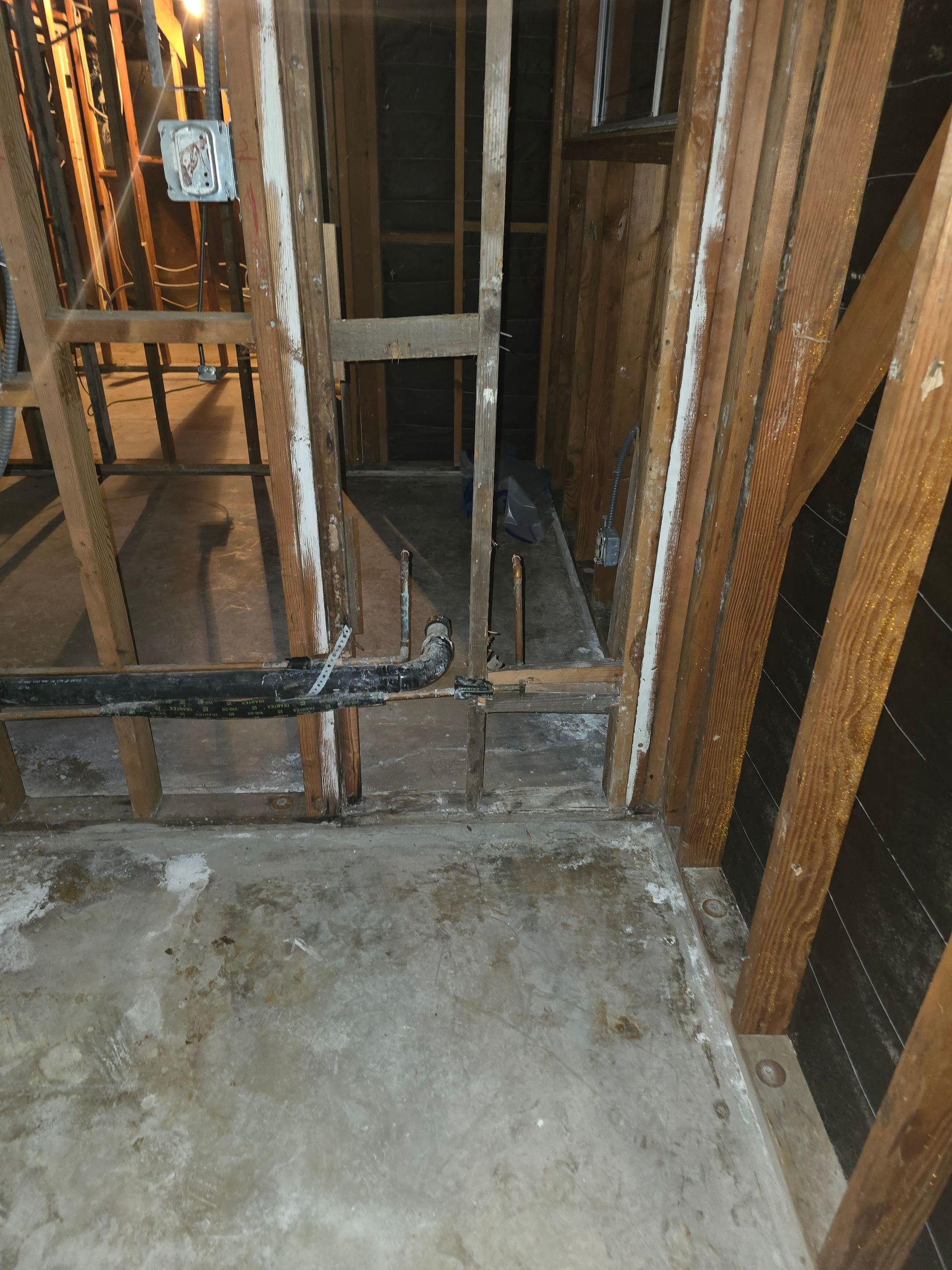 Damaged indoor wall framing and exposed studs around a concrete floor opening