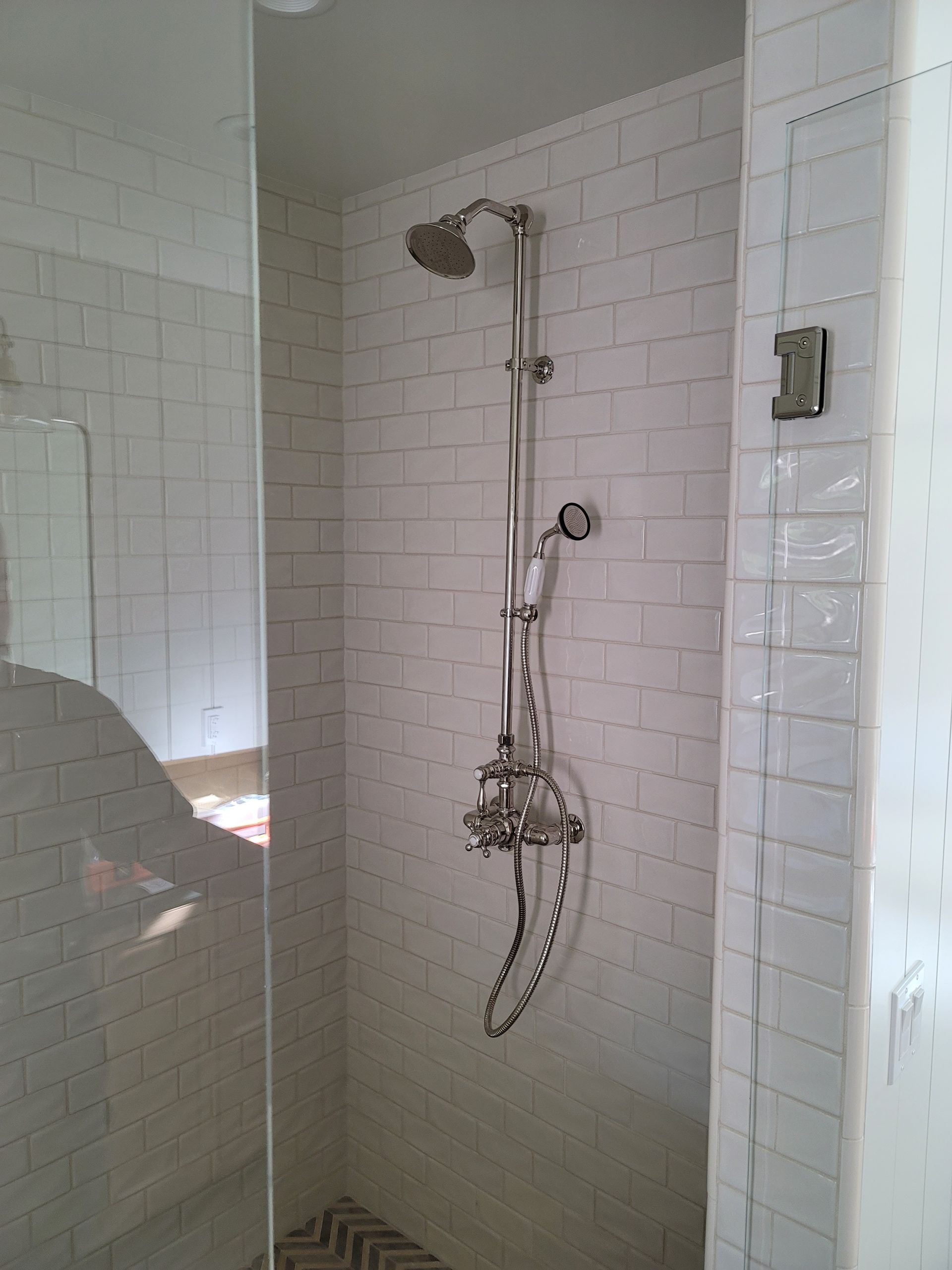 Shower stall with white subway tile and chrome fixtures in a bathroom