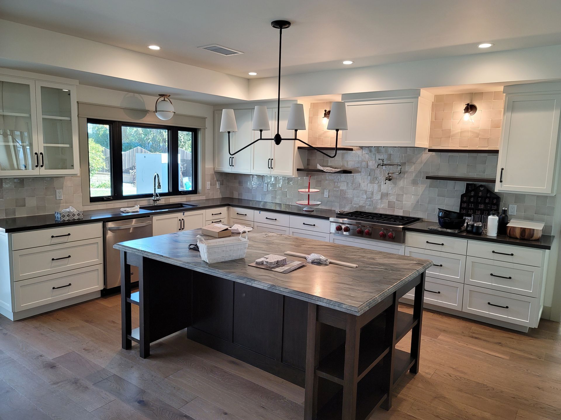 Modern kitchen with white cabinets, marble island, and stainless appliances under pendant lights