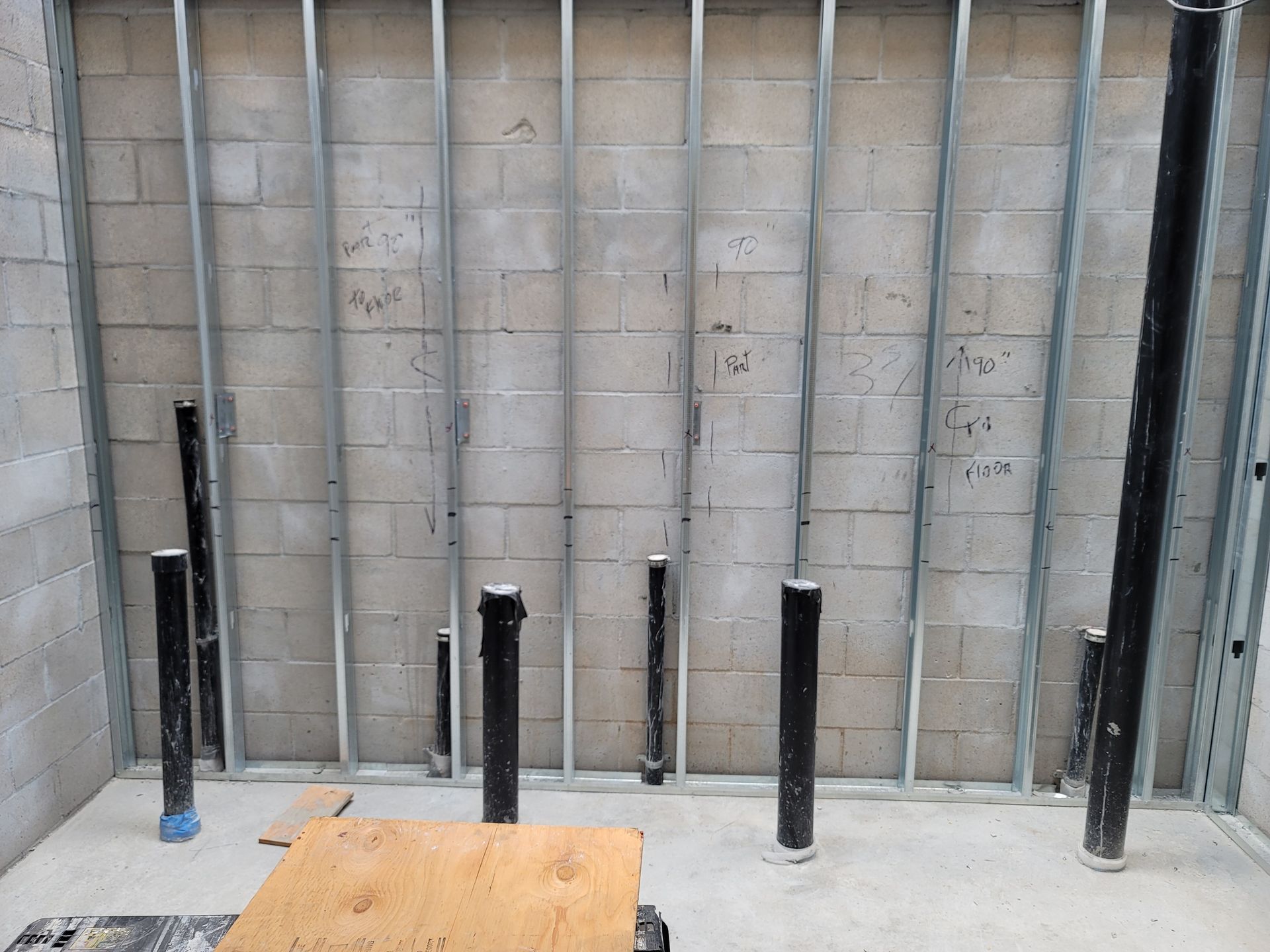 Concrete wall with several black steel posts and a wooden platform in the foreground