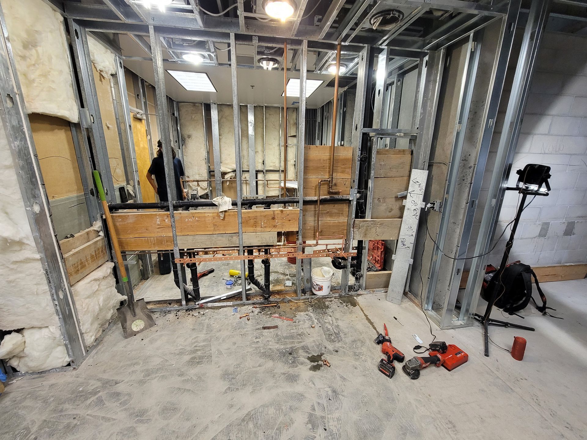 Partially framed room under renovation with exposed studs, tools, and concrete floor.