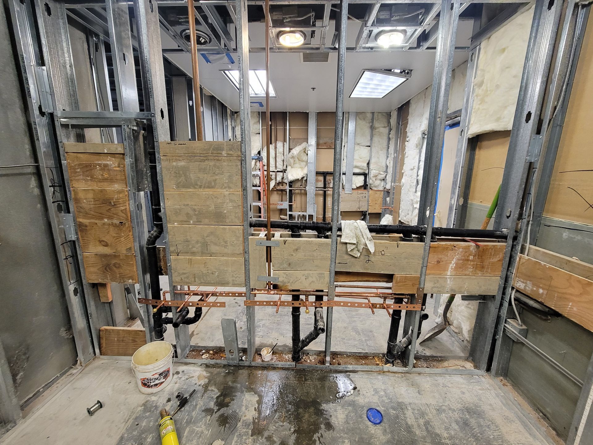 Partially framed bathroom under construction with exposed studs, plumbing, and concrete floor
