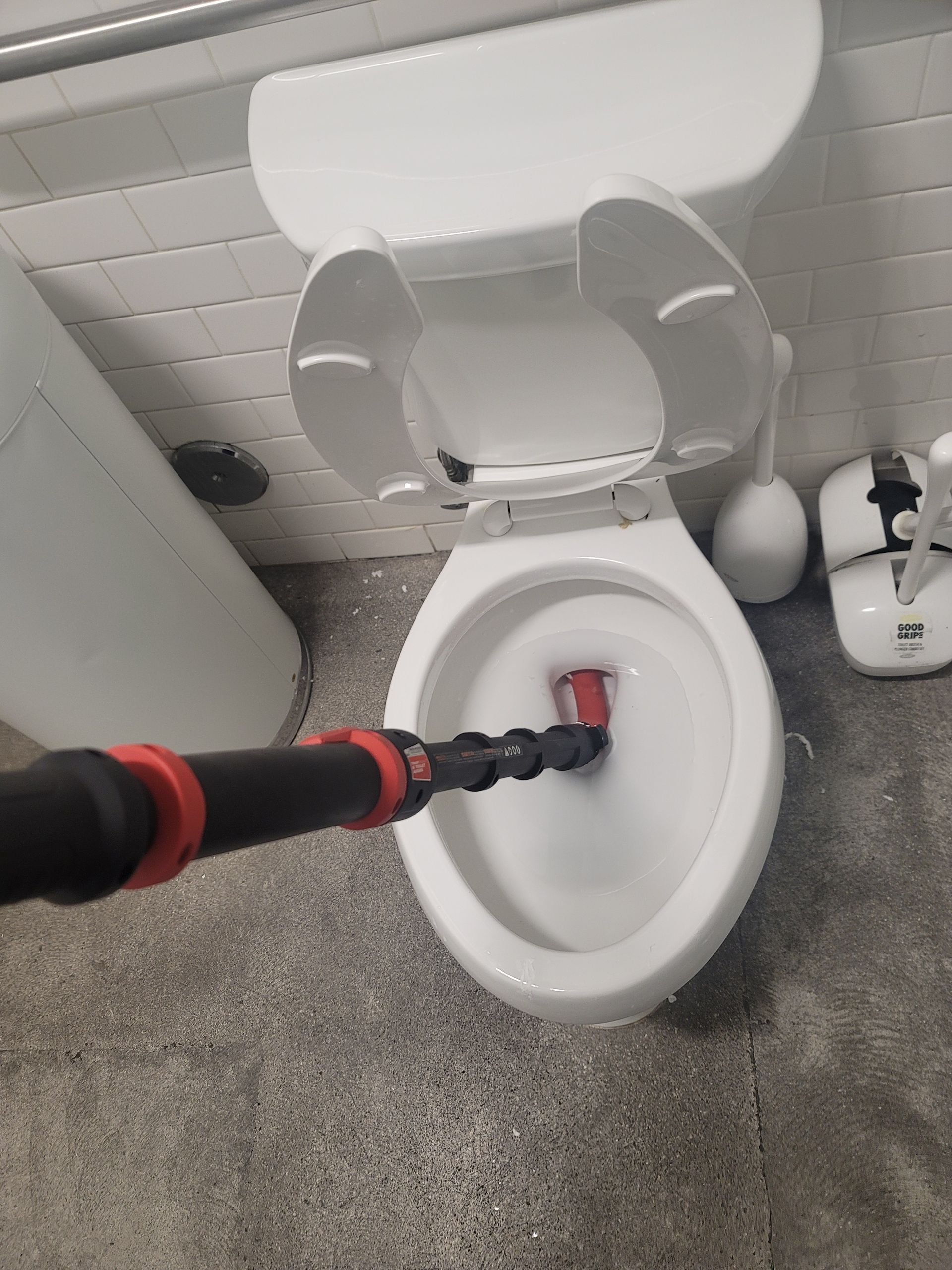 Handheld vacuum cleaning inside a white toilet bowl in a bathroom