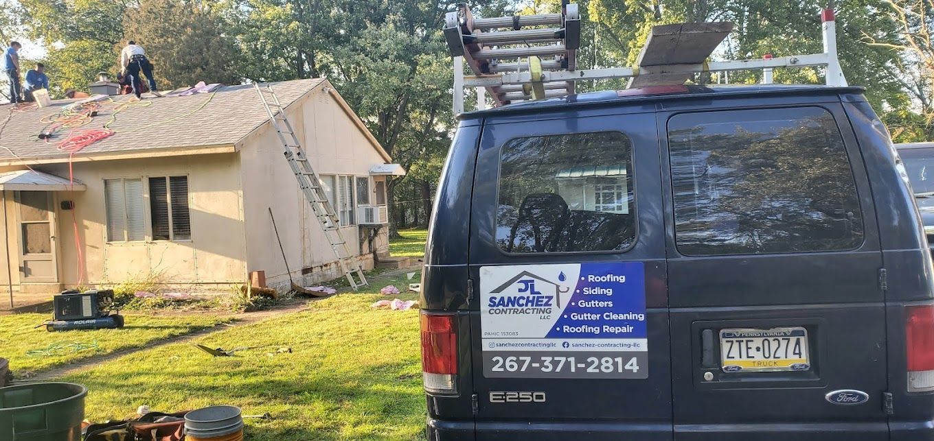 A van is parked in front of a house with a ladder on top of it.