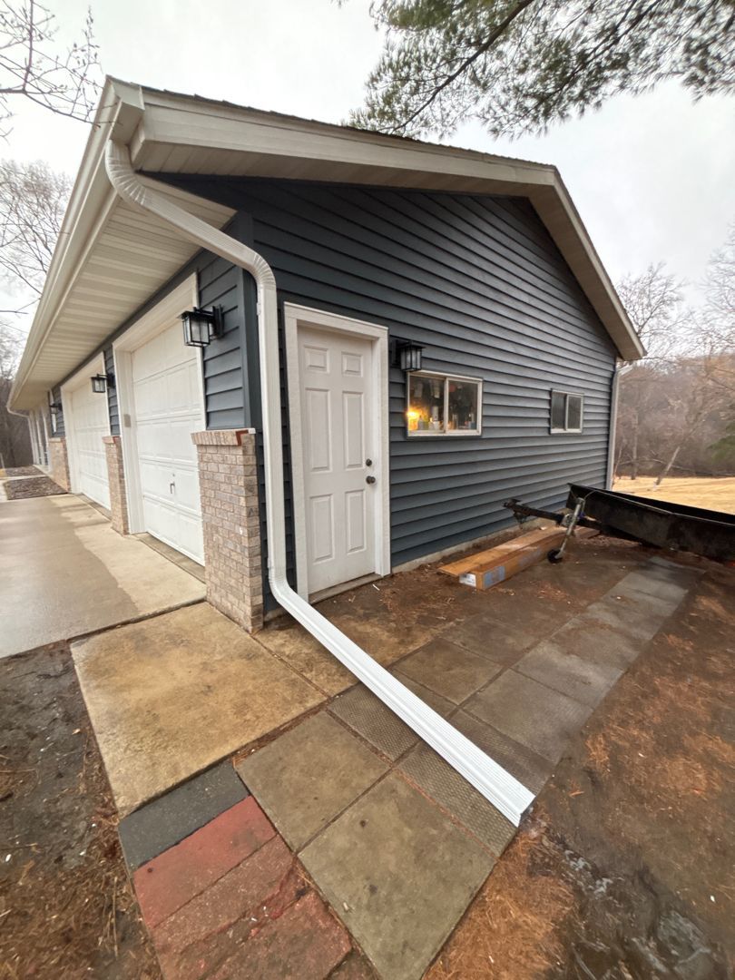 A blue garage with a white door and a white gutter.