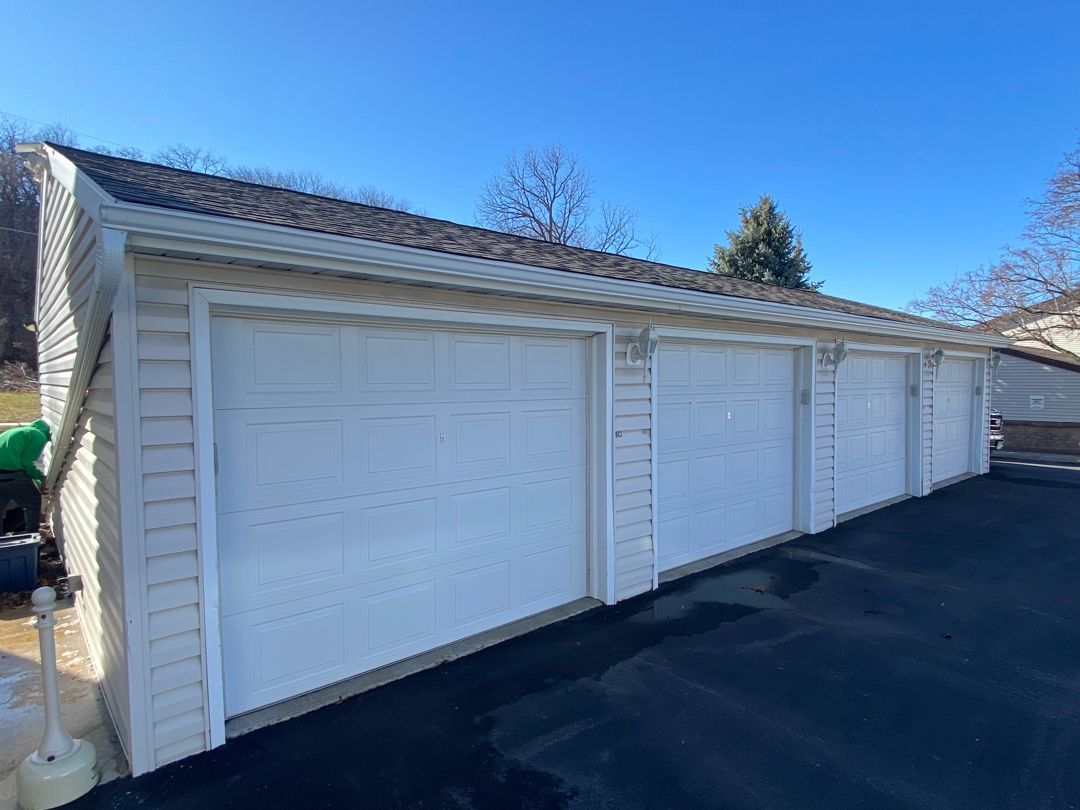 A row of white garage doors on a sunny day.