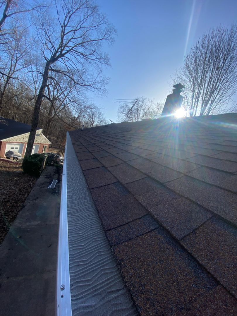 A roof with a white gutter and a chimney on it.