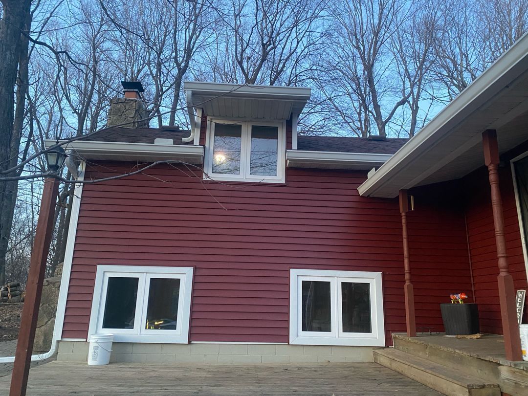 A red house with white windows and a chimney on the roof.