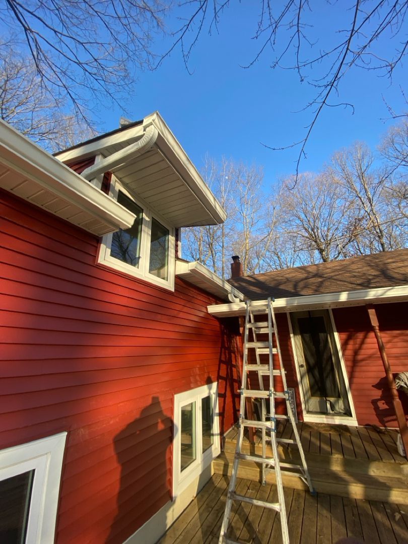 A red house with a ladder on the side of it.