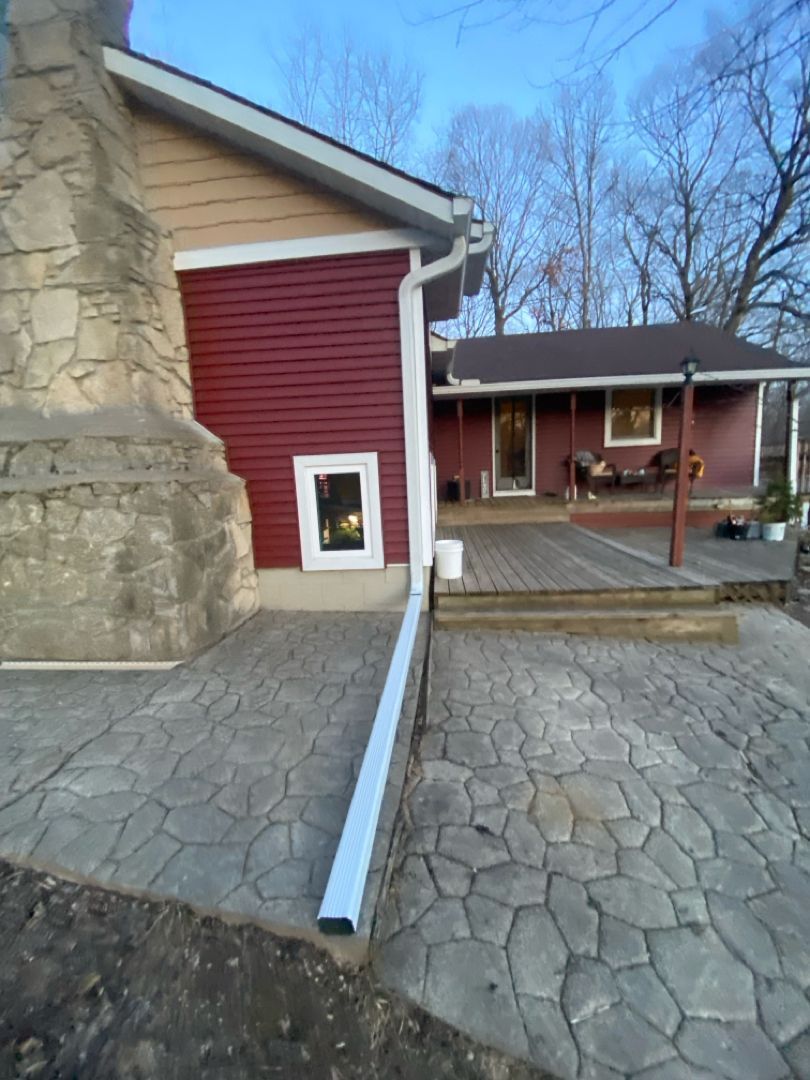 A red house with a white gutter on the side of it.