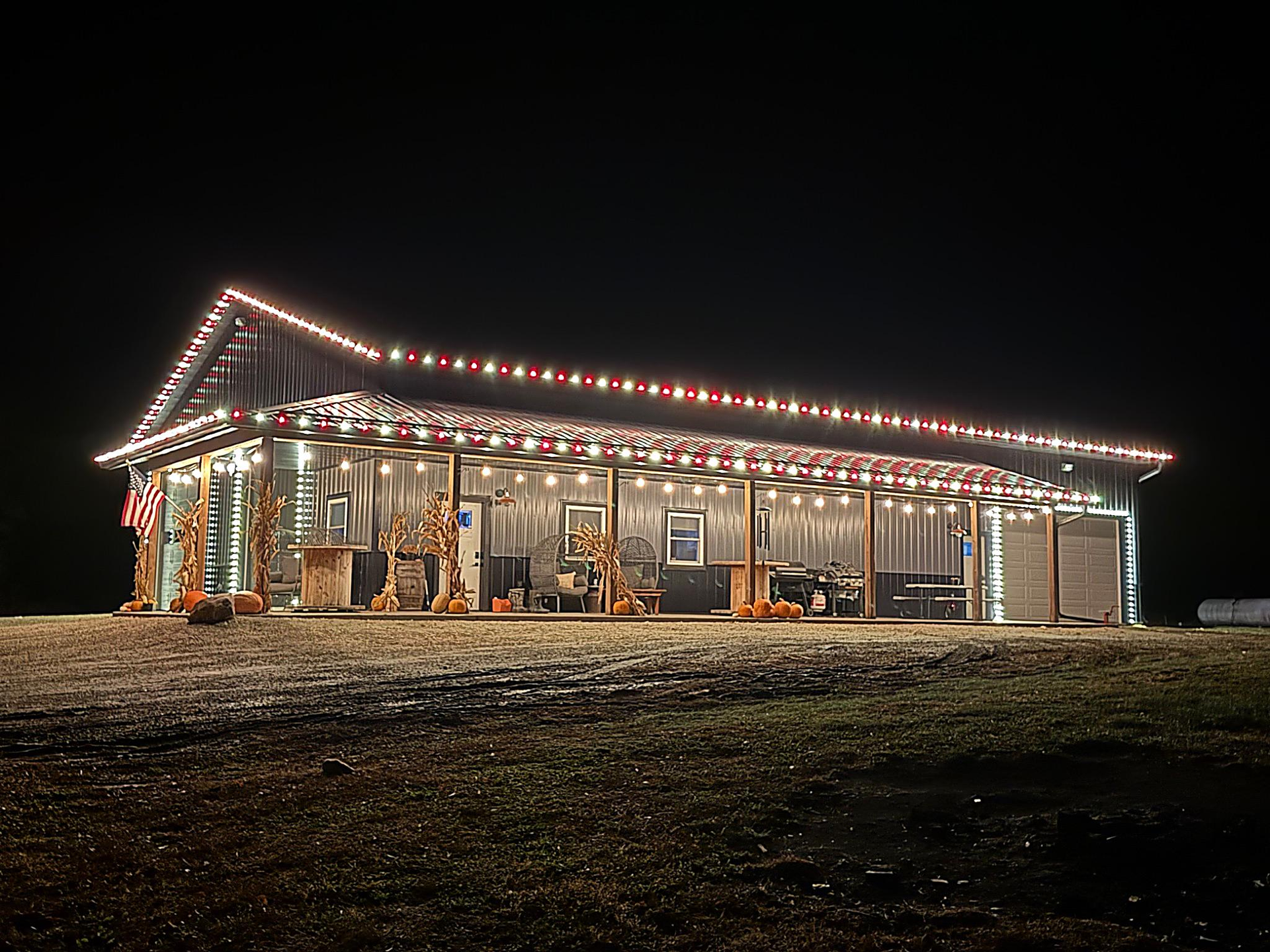 A large barn is lit up with Christmas lights at night.