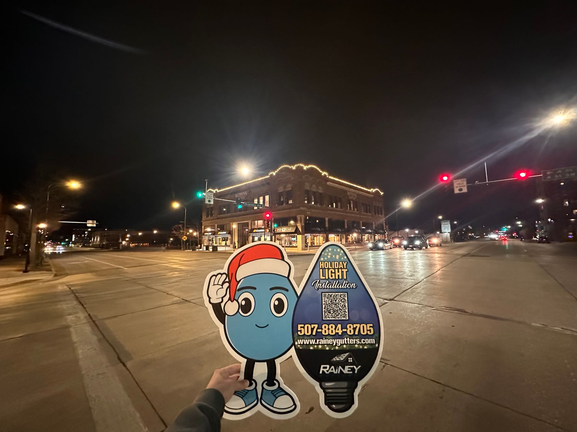 A person is holding a sign in front of a building at night.