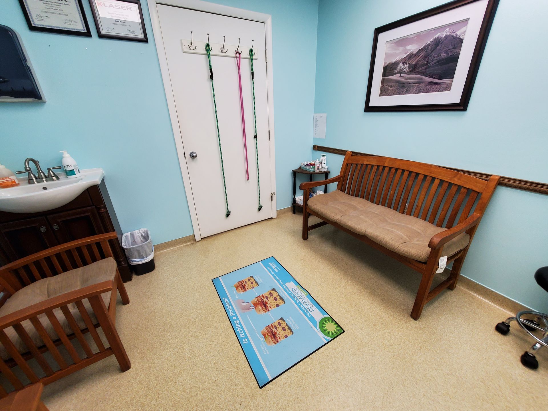 A waiting room with a bench , chairs , a sink and a rug.