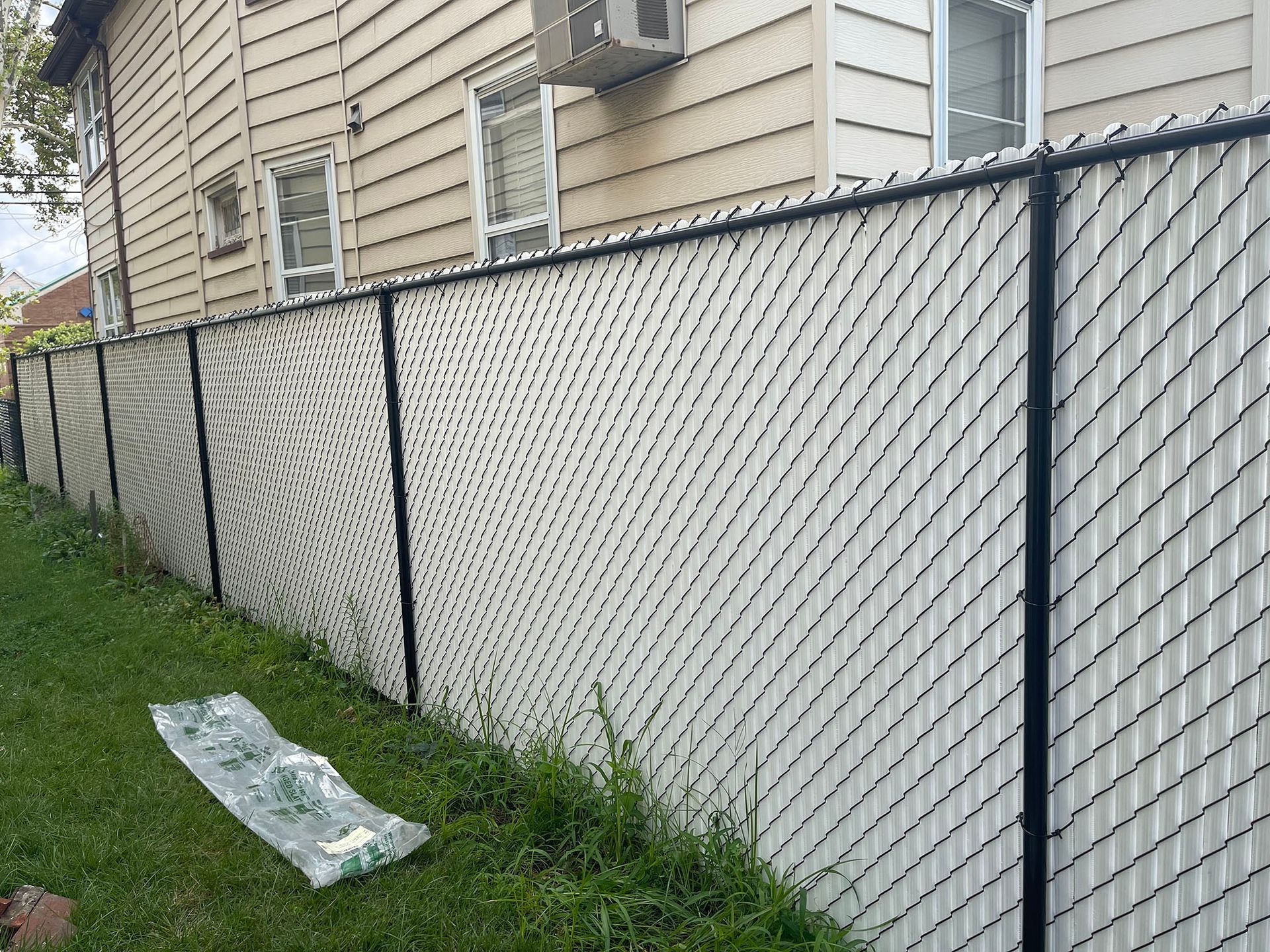 A white chain link fence is sitting in front of a house.
