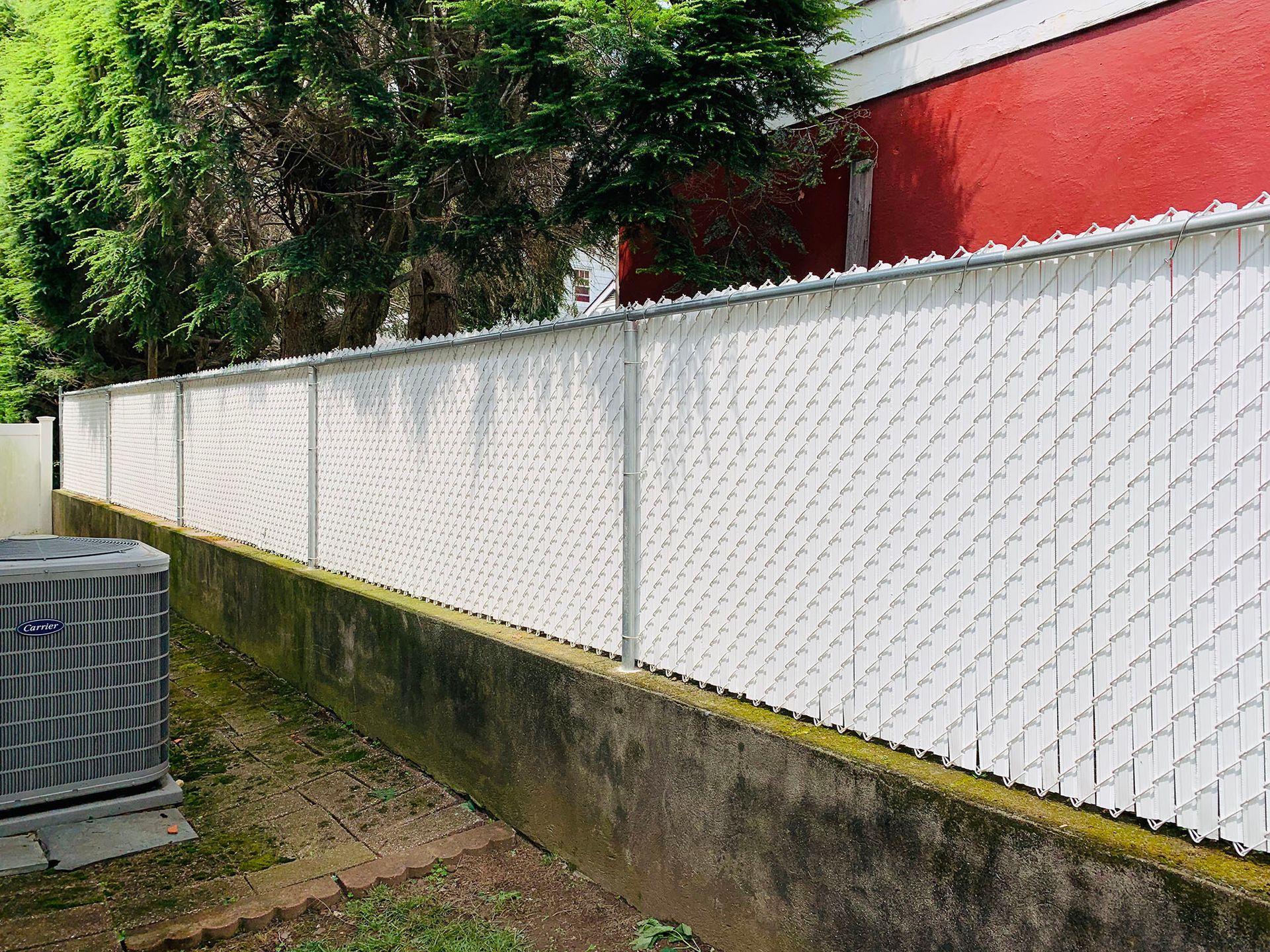 A white chain link fence is sitting next to a red building.