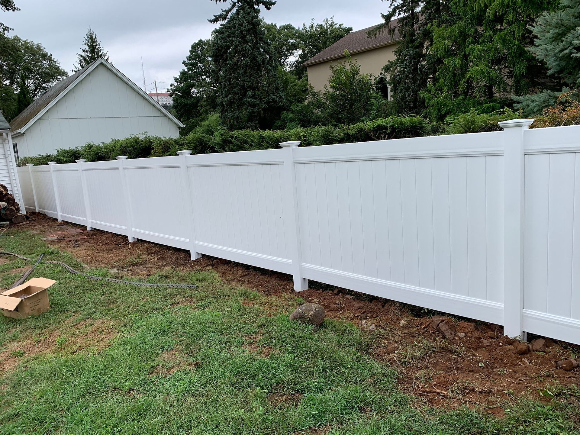 A white fence is sitting in the middle of a lush green yard.