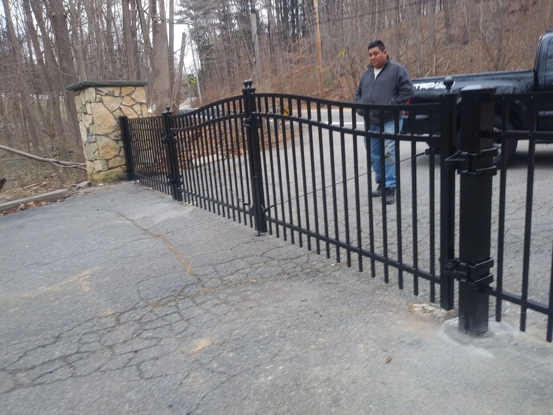 A man is standing in front of a black fence.