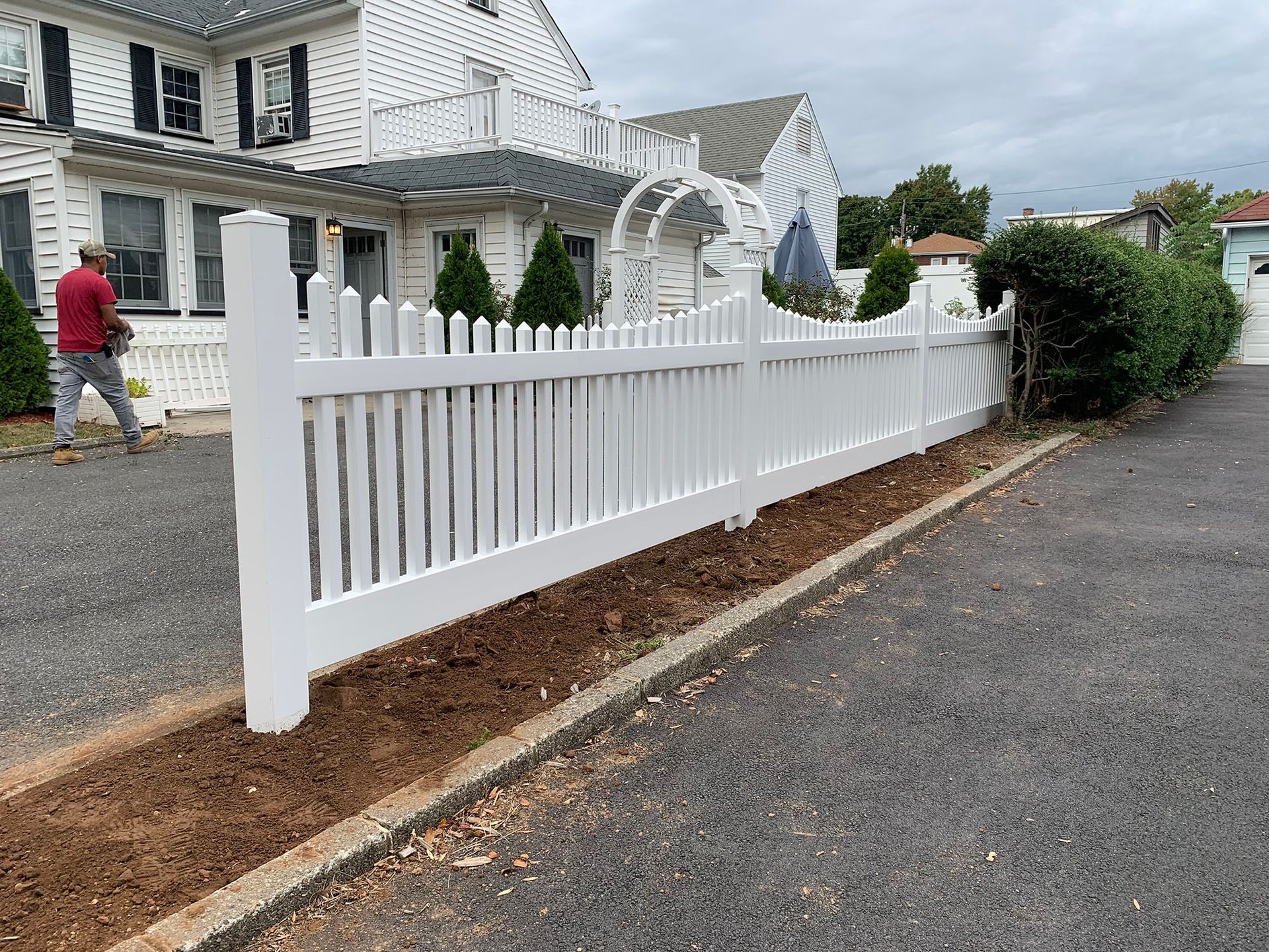 A white picket fence is in front of a white house.