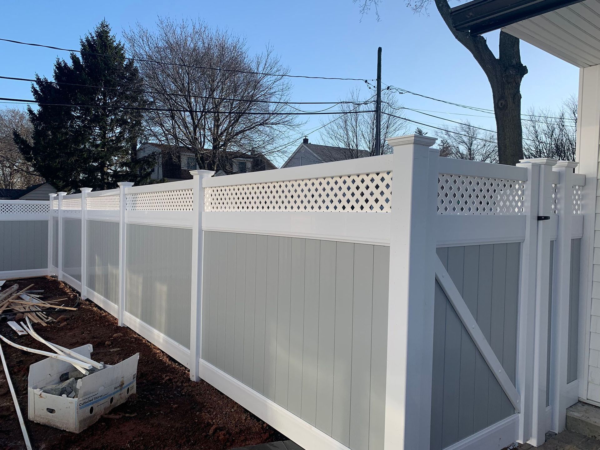 A white and gray fence with a gate in front of a house.
