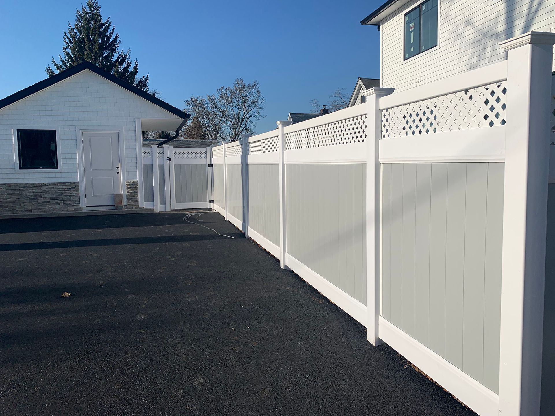 A white and gray fence is surrounding a white house.