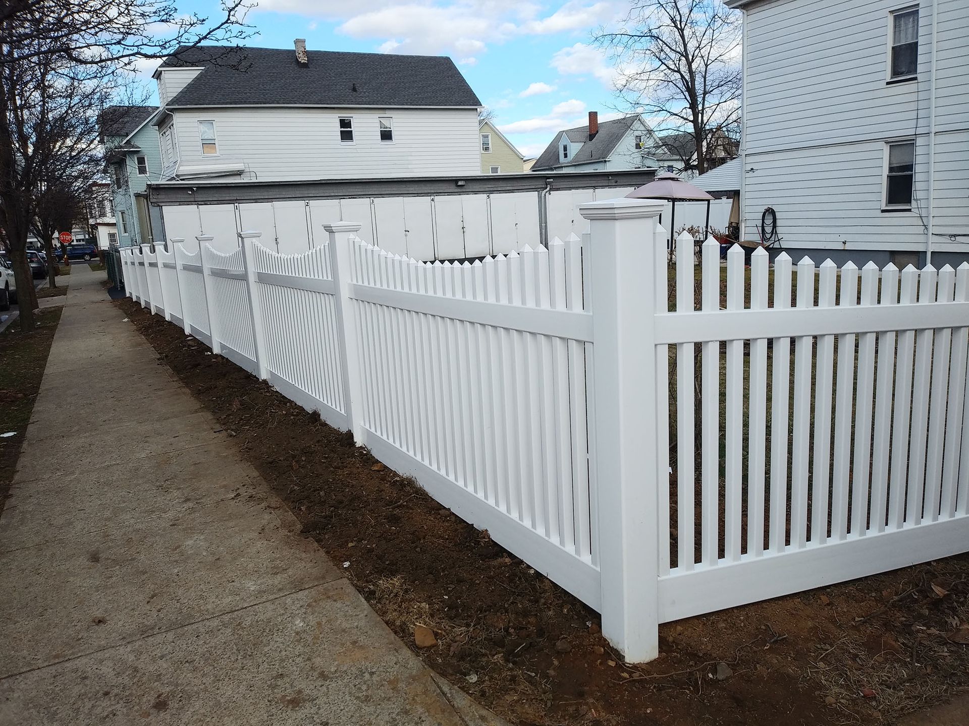 A white picket fence along a sidewalk in front of a house
