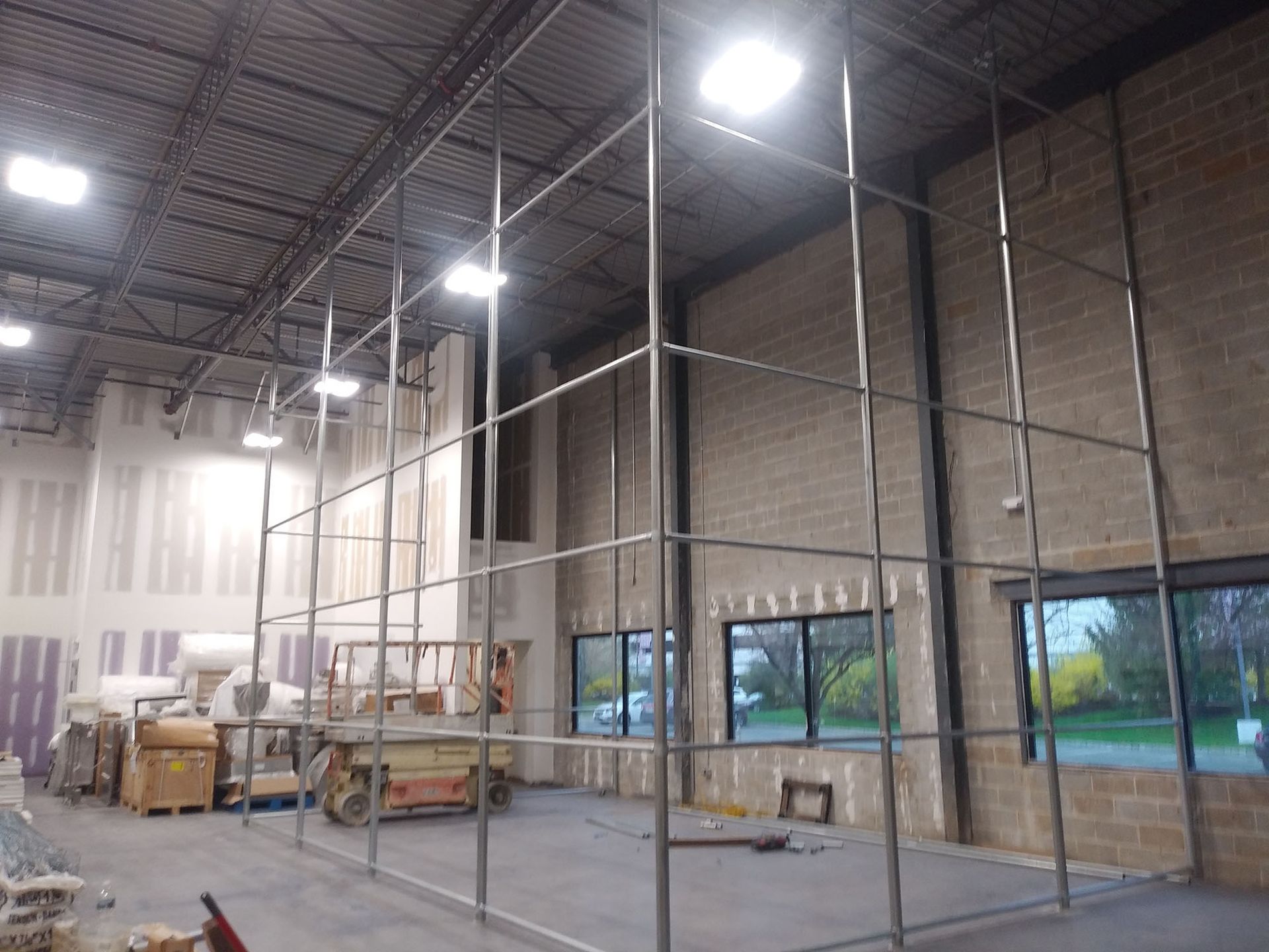 A large metal structure is being built inside of a brick building.