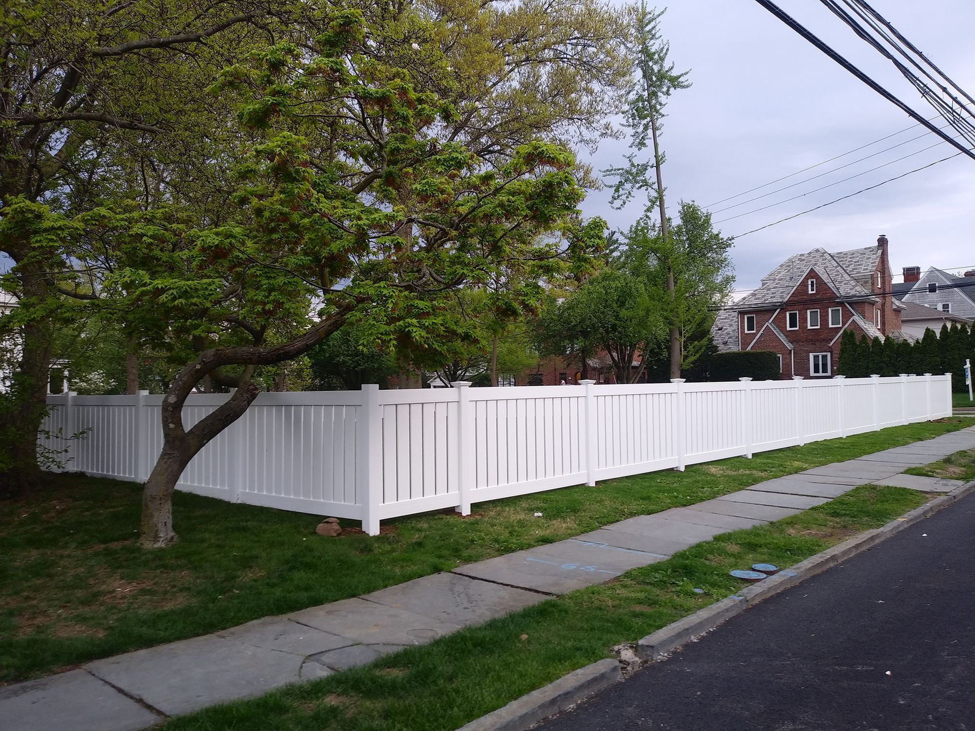 A white fence along a sidewalk in front of a house