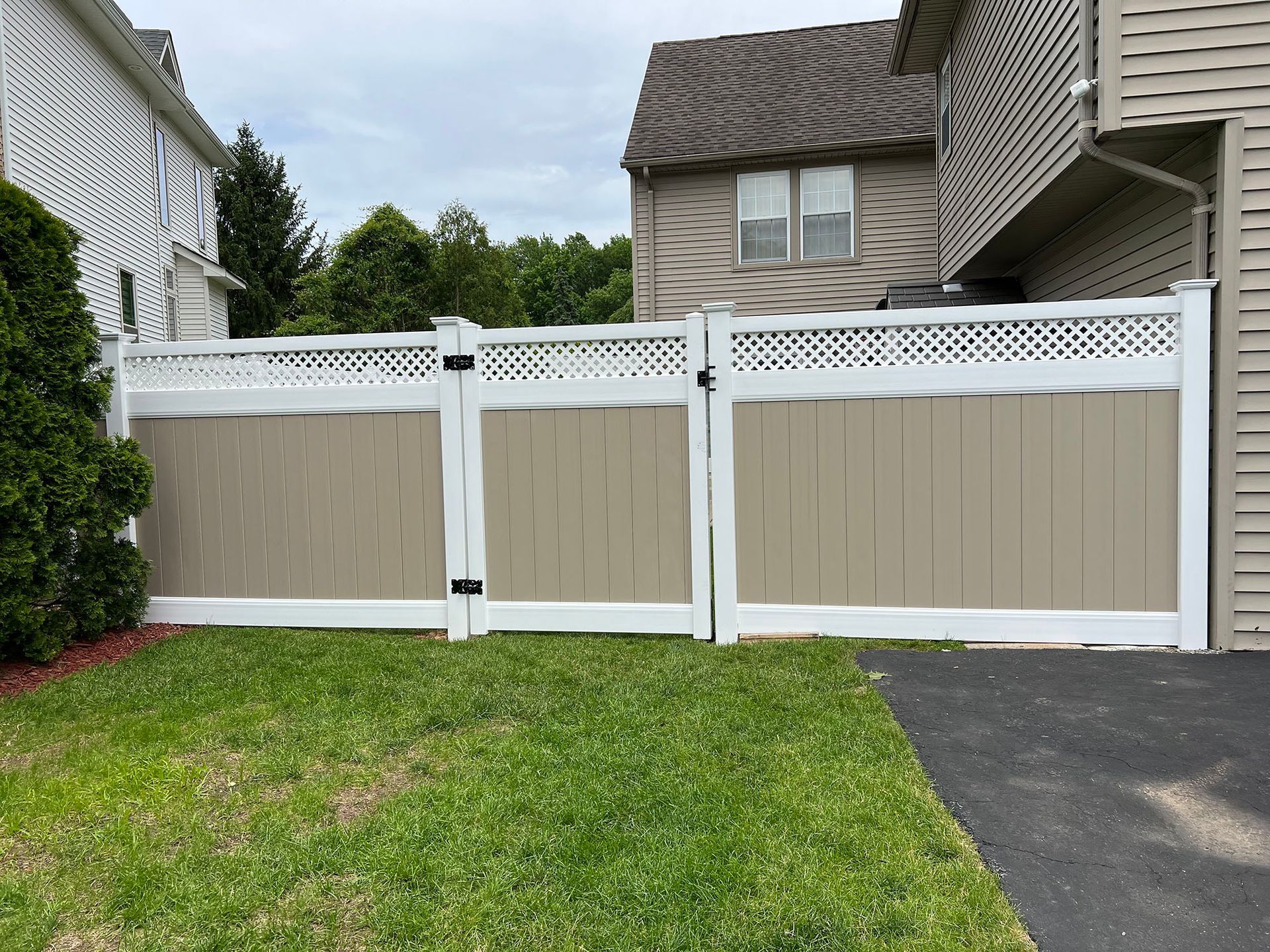 A white and tan fence is in front of a house.