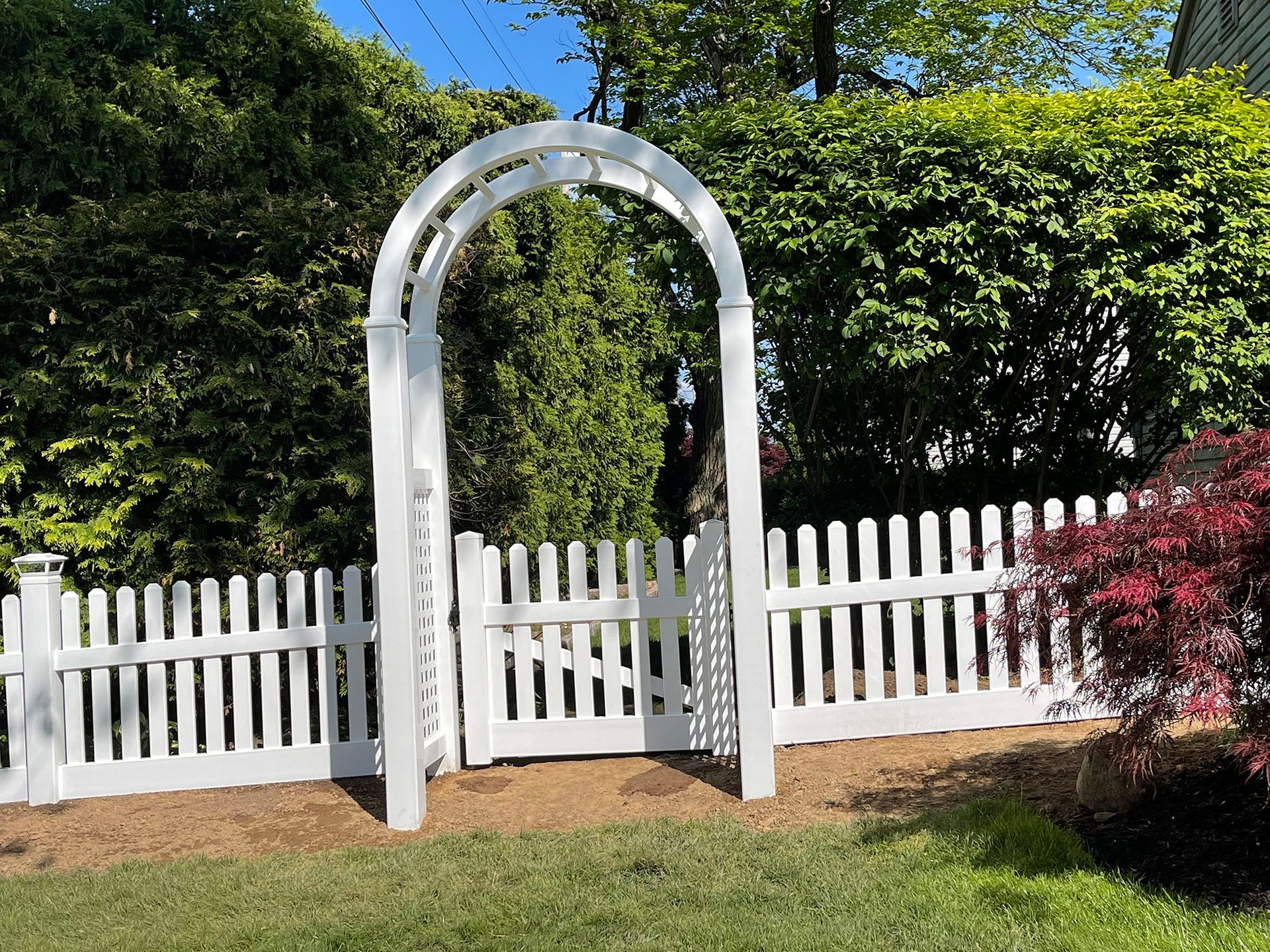 A white picket fence with an archway in the middle