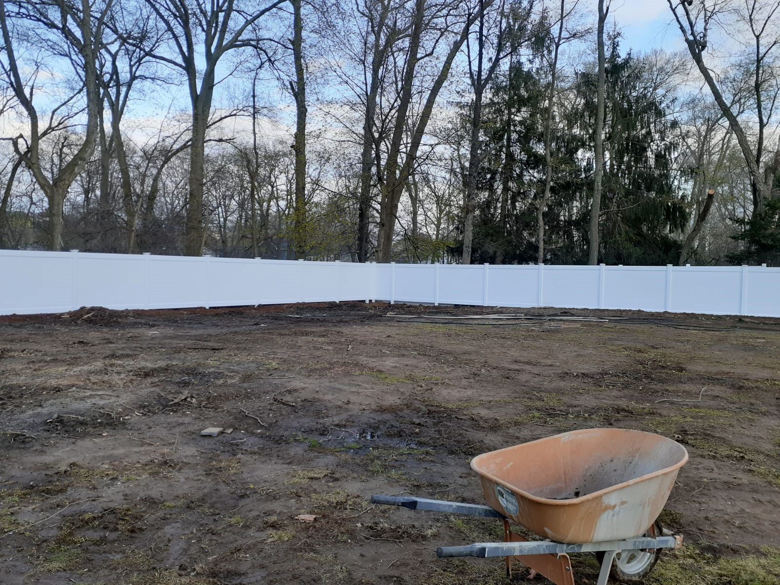 A wheelbarrow is sitting in the middle of a dirt field.