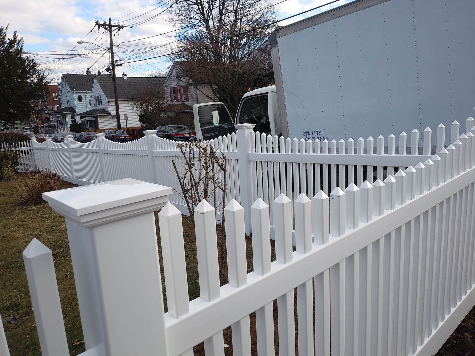 A white picket fence with a white truck in the background