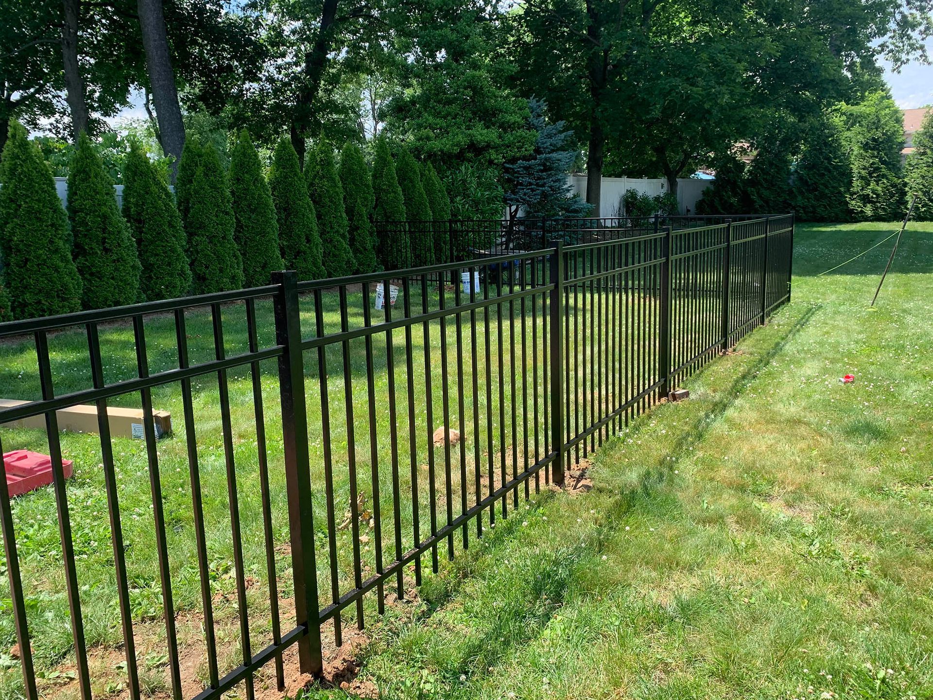 A black wrought iron fence surrounds a lush green lawn.