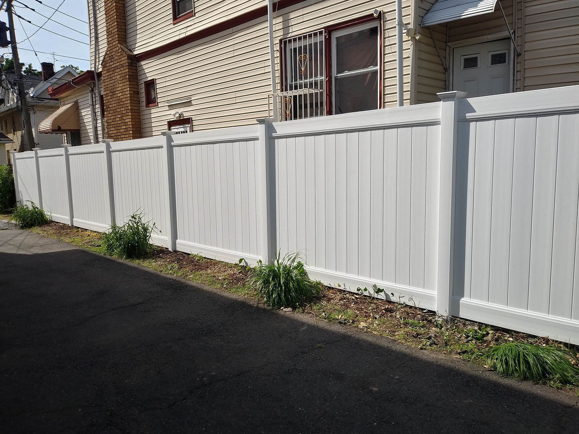 A white fence along the side of a road next to a house