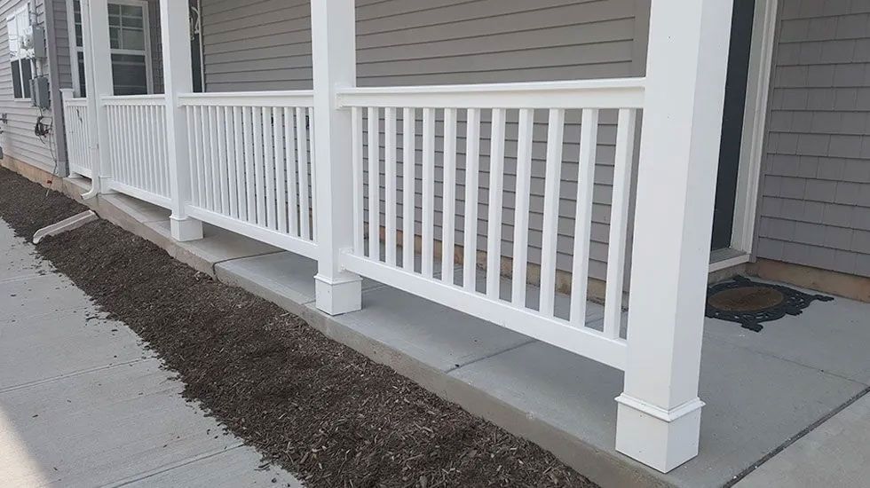 A white porch railing on the side of a house.