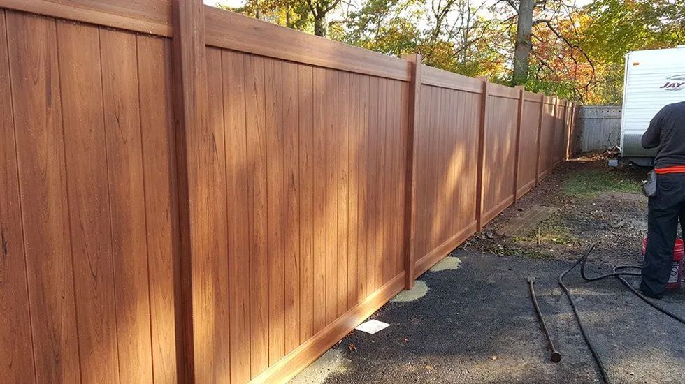 A man is working on a wooden fence next to a trailer.