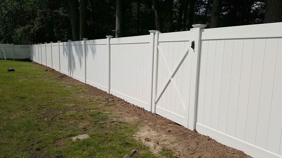 A white vinyl fence with a gate in the backyard.