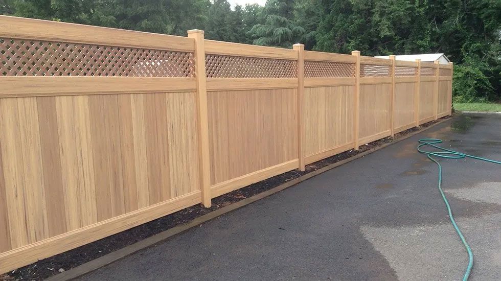 A wooden fence is sitting on the side of a road next to a hose.