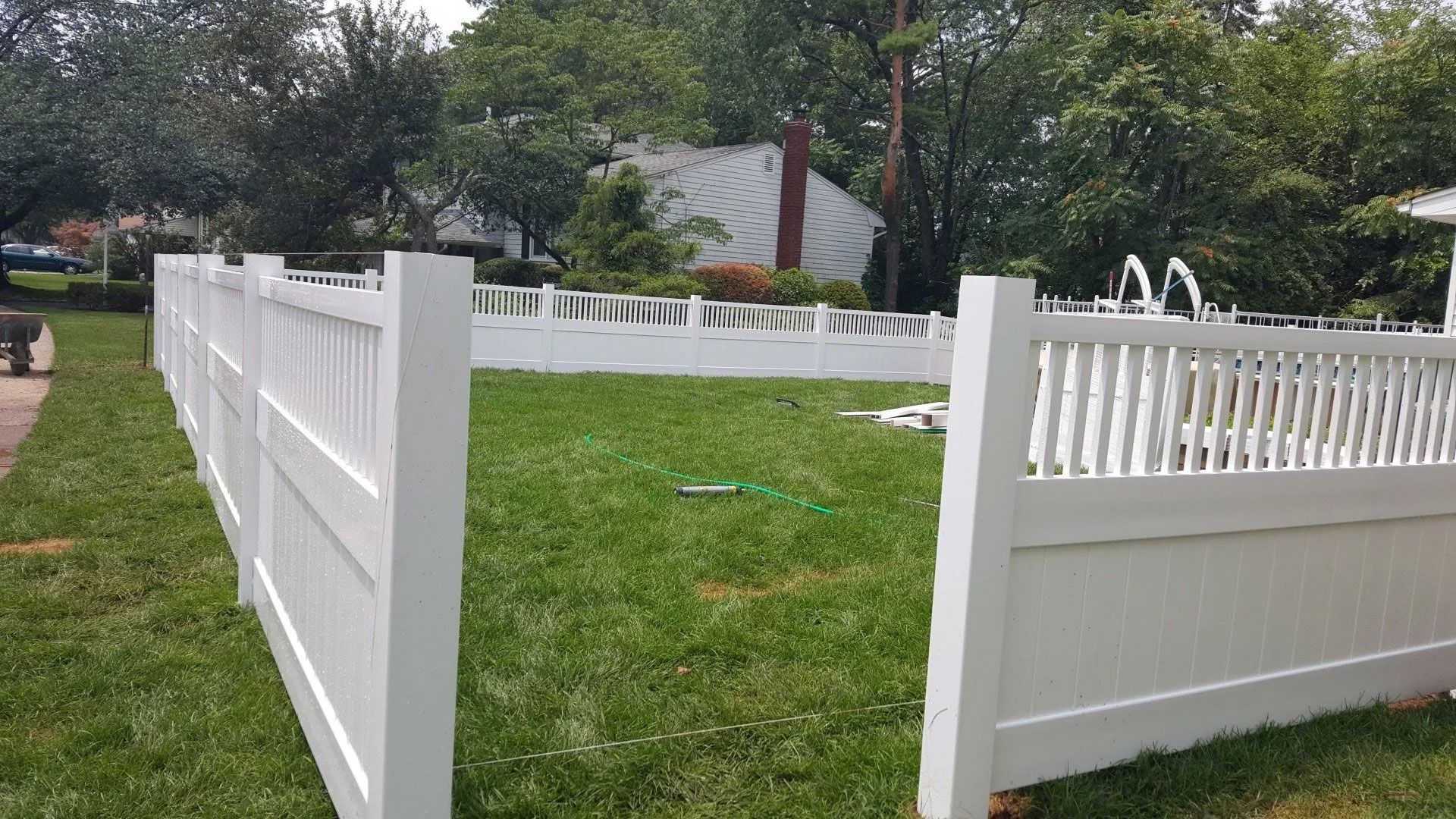 A white fence is in the middle of a lush green yard.
