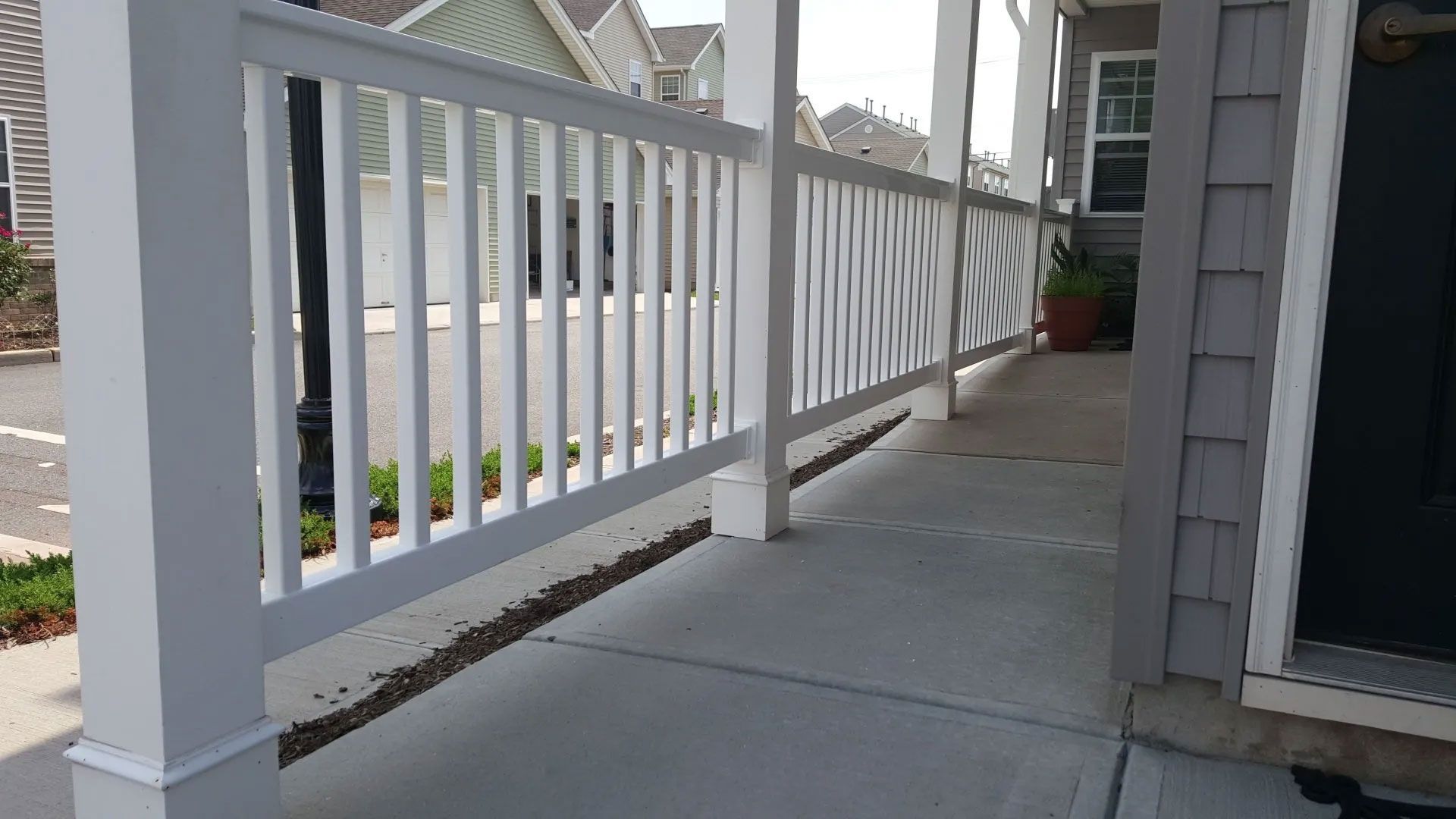 A white railing on a porch next to a house.