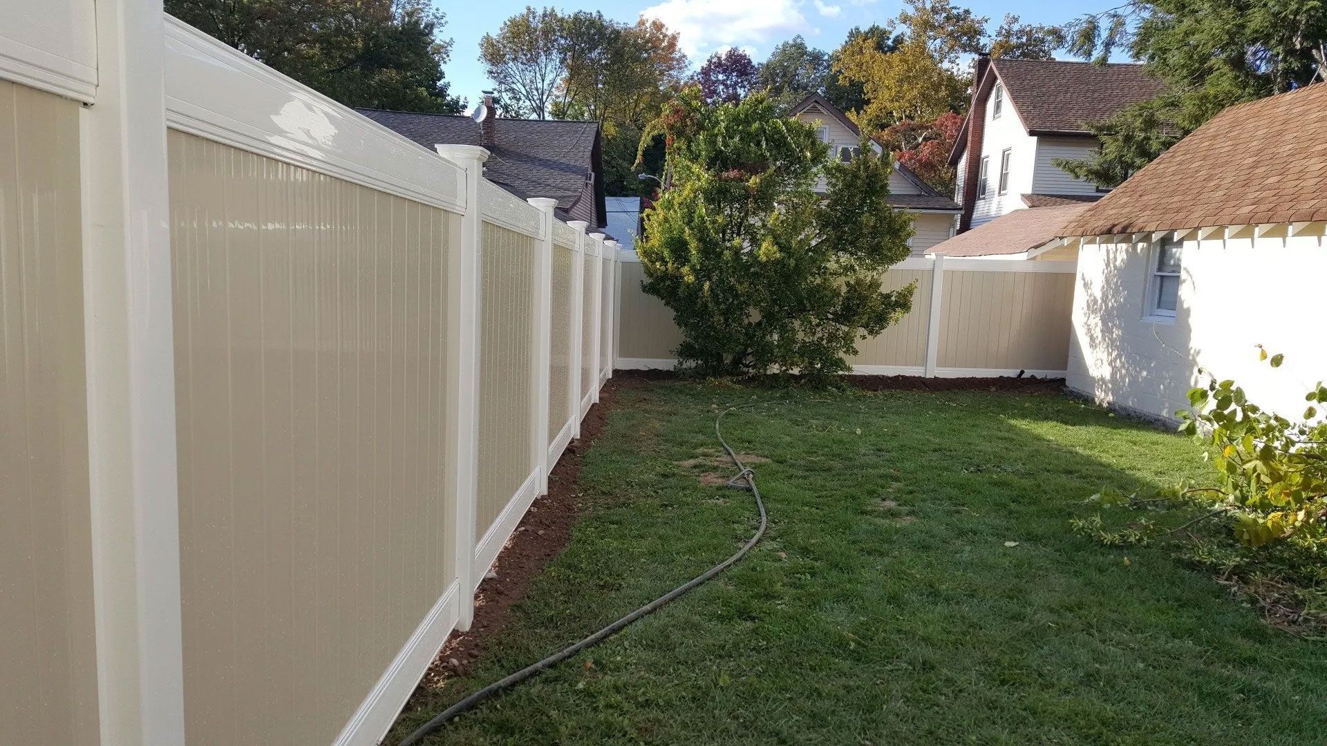 A white fence is in the backyard of a house.