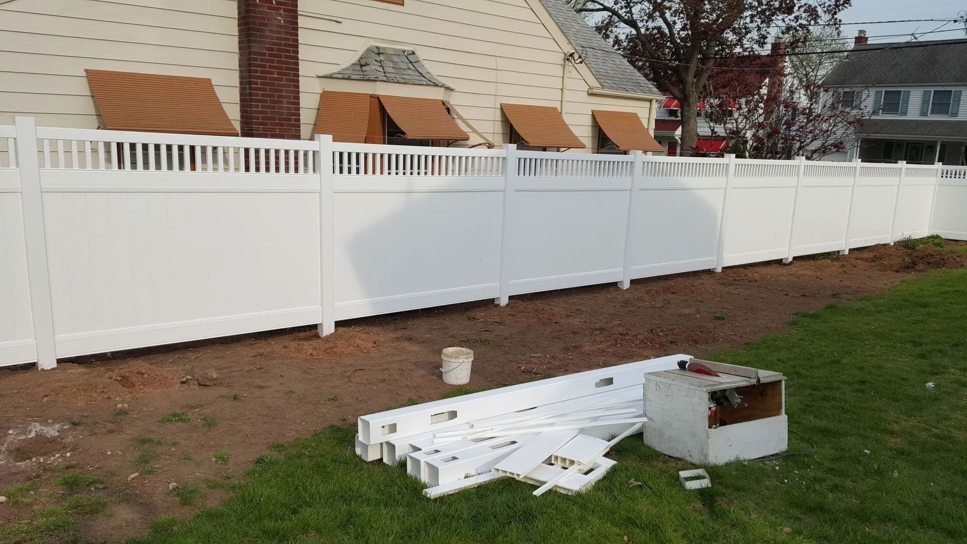 A white fence is being built in front of a house.