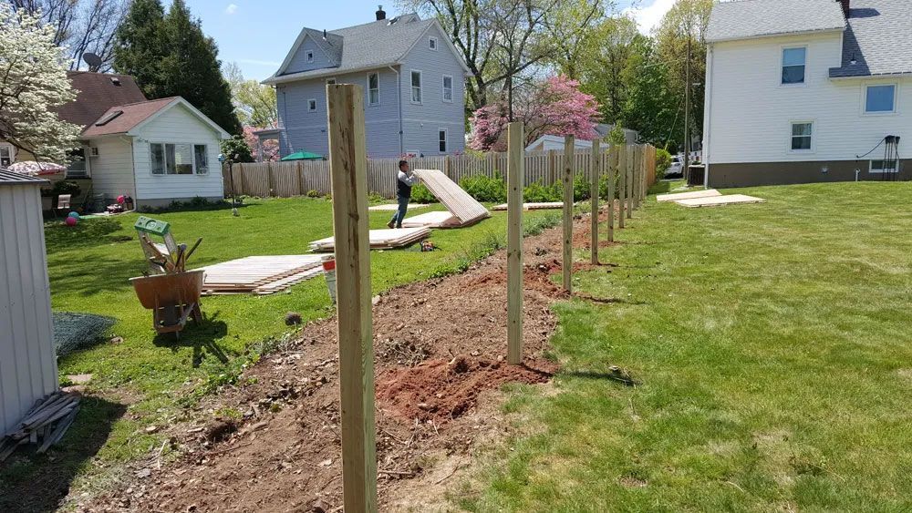 A wooden fence is being built in the backyard of a house.