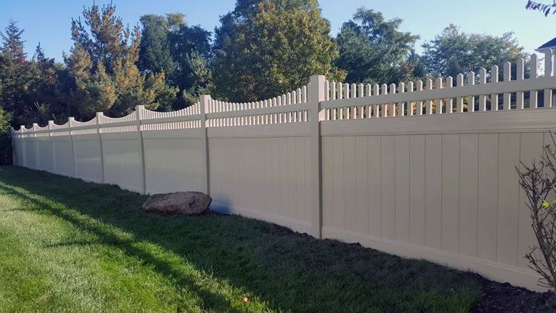 A white vinyl fence is sitting in the middle of a lush green yard.