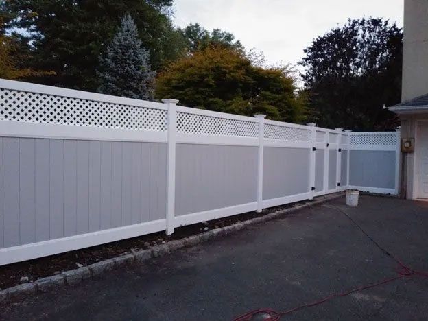 A white fence with a lattice design is in front of a house